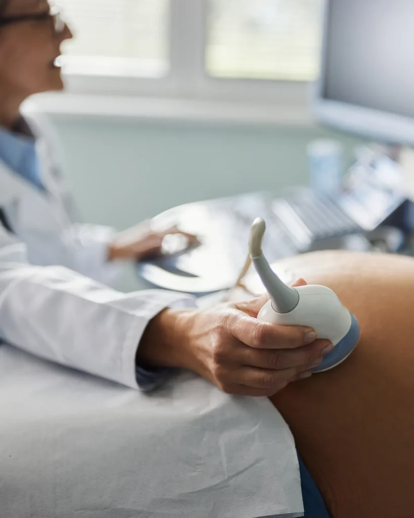 Close up of a female gynecologist having an ultrasound exam on pregnant woman in the office office.