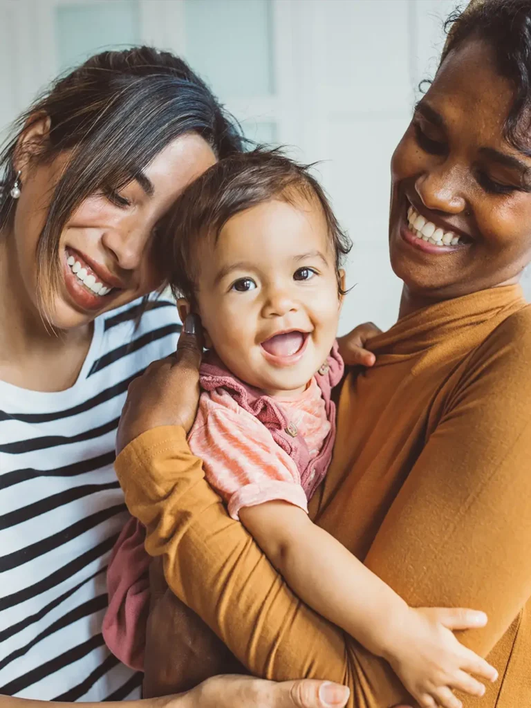 Young mothers playing with baby girl in living room.