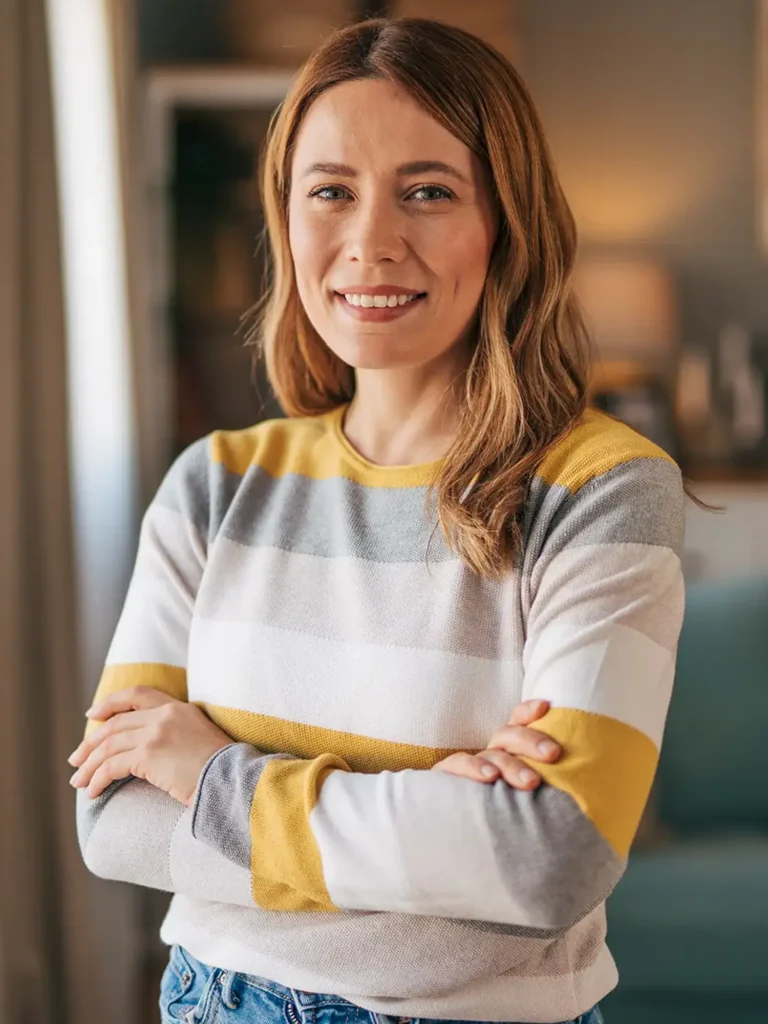 Portrait of a mature woman standing in her living room with her arms crossed.